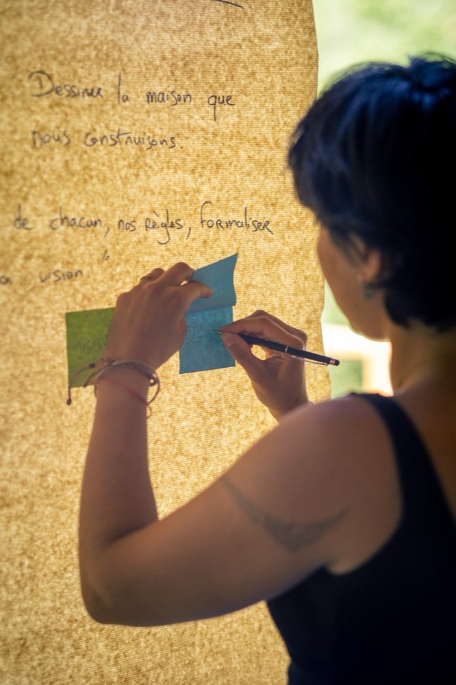 Une participante écrit sur un post-it pendant un atelier du séminaire Fyneo